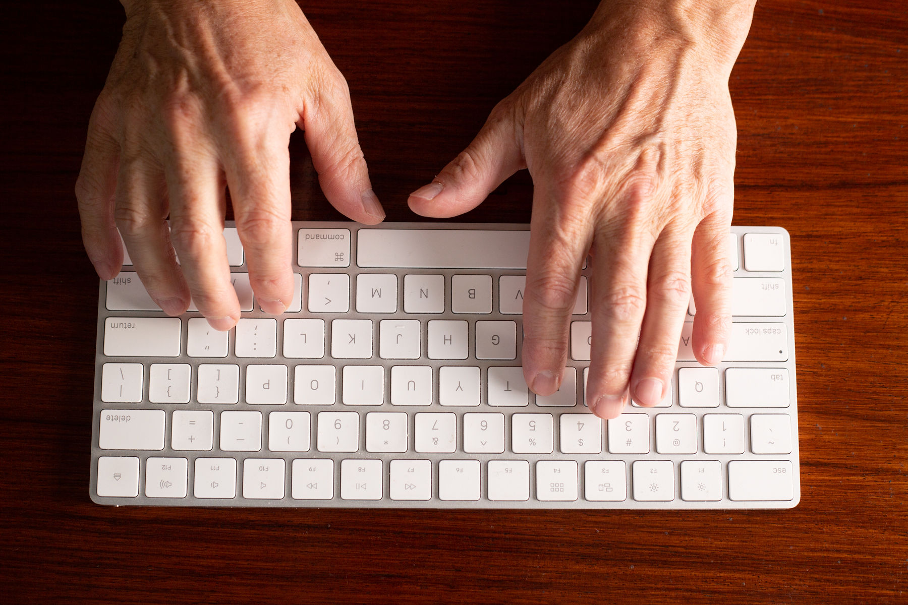 two hands typing on a computer keyboard